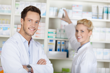 Portrait of a smiling pharmacists team smiling in front of medicines at drugstore